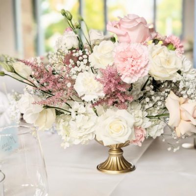 Runde Hochzeitstafel mit großem Blumen-Centerpiece in Rosa, Blau und Weiß in goldenem Gefäß – dekoriert von Pfirsichkoeppchen Weddings.